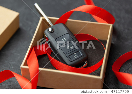 Gift box with car keys with remote control alarm system with red ribbon bow. 47117709