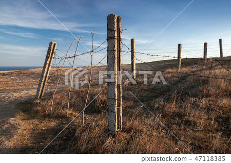 Old barbed wire fence is on dry grass 47118385