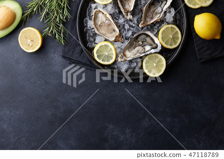 Fresh oysters in a plate with ice on black table Fresh oysters in a plate with ice on black table 47118789