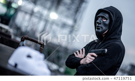 Mystery man in black mask holding gun 47119751
