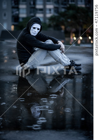 Mystery man in white mask sitting in the rain 47119756