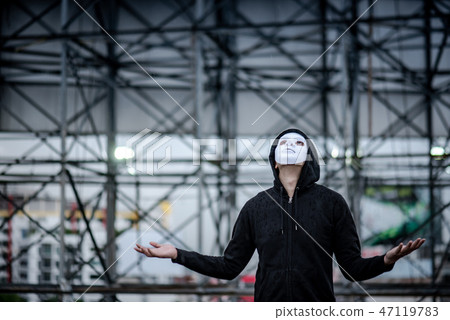 Mystery man in white mask standing in the rain 47119783