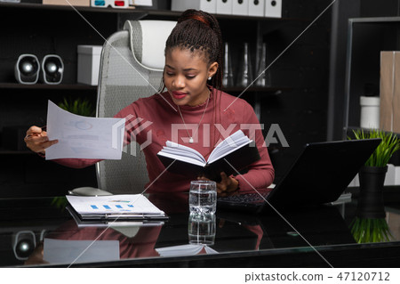 young African-American businesswoman working with documents and notebook at computer Desk in office 47120712