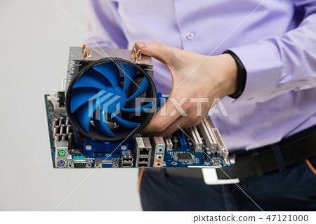 Cooler and motherboard in men's hands close-up isolated on light background Cooler and motherboard in men's hands close-up isolated on light background 47121000