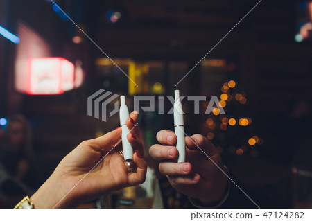 IQOS heat-not-burn tobacco product technology. Man holding e-cigarette in his hand before smoking. IQOS heat-not-burn tobacco product technology. Man holding e-cigarette in his hand before smoking. 47124282
