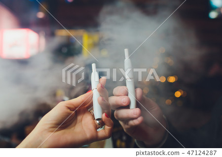 IQOS heat-not-burn tobacco product technology. Man holding e-cigarette in his hand before smoking. 47124287