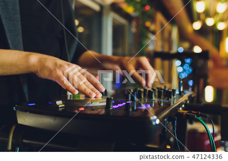 DJ playing music at mixer closeup and mixes the track in the nightclub at party. DJ playing music at mixer closeup and mixes the track in the nightclub at party. 47124336
