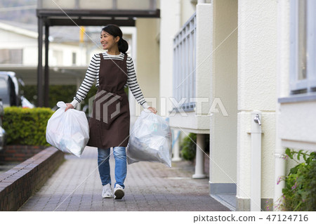 A woman holding a garbage bag A woman holding a garbage bag 47124716
