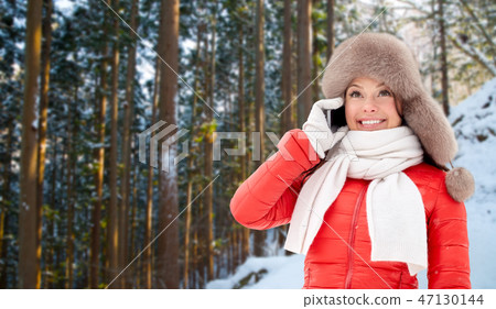 woman calling on smartphone over winter forest 47130144