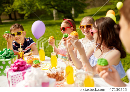 kids eating cupcakes on birthday party in summer 47130223