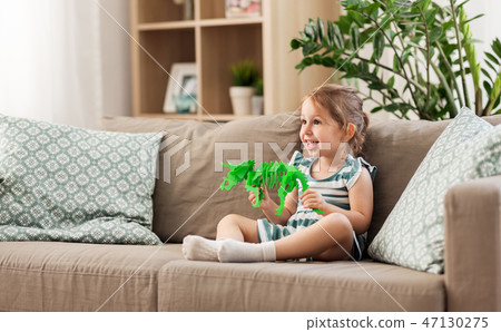happy baby girl playing with toy dinosaur at home 47130275