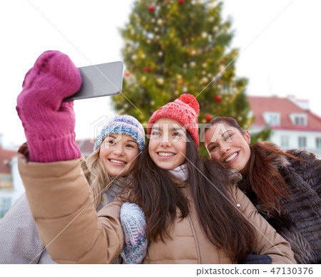 teenage girls taking selfie over christmas tree teenage girls taking selfie over christmas tree 47130376