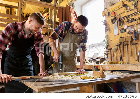 carpenters working with wooden board at workshop carpenters working with wooden board at workshop 47130569