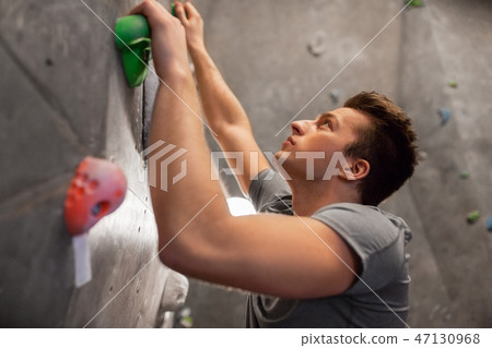 young man exercising at indoor climbing gym young man exercising at indoor climbing gym 47130968
