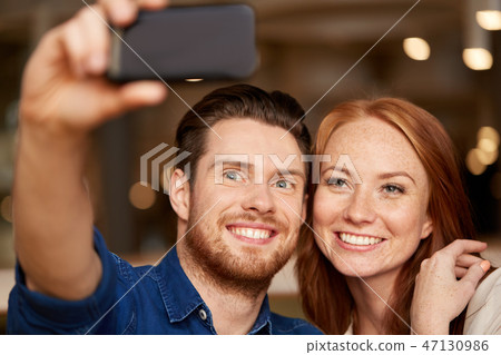 couple taking selfie by smartphone at restaurant couple taking selfie by smartphone at restaurant 47130986