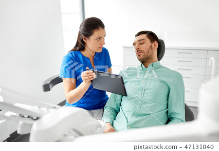 dentist and patient with tablet pc at clinic dentist and patient with tablet pc at clinic 47131040