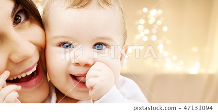close up of mother with baby over christmas lights close up of mother with baby over christmas lights 47131094