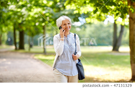 senior woman calling on smartphone in summer park senior woman calling on smartphone in summer park 47131329