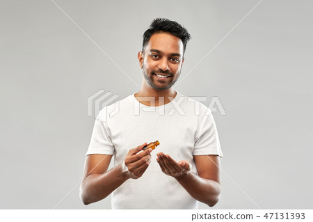 indian man applying grooming oil to his hand indian man applying grooming oil to his hand 47131393