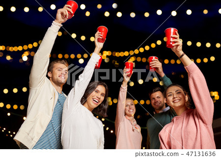 friends toasting party cups on rooftop at night friends toasting party cups on rooftop at night 47131636