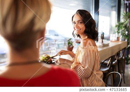 female friends eating at restaurant female friends eating at restaurant 47131685