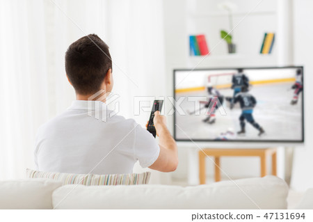 man watching ice hockey game on tv at home man watching ice hockey game on tv at home 47131694