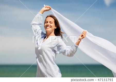 happy woman with shawl waving in wind on beach 47131791