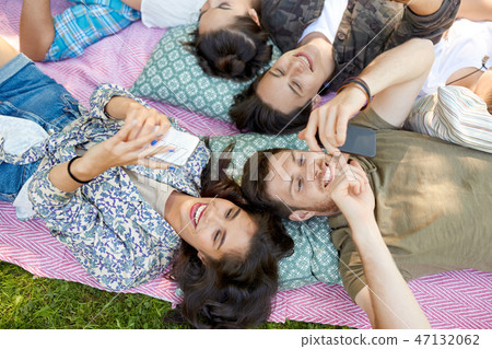 friends with smartphones chilling at summer park friends with smartphones chilling at summer park 47132062