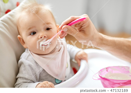 father feeding baby sitting in highchair at home father feeding baby sitting in highchair at home 47132189