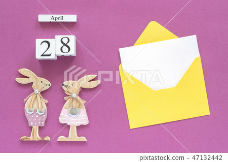 Calendar April 28, pair wooden easter bunnies, yellow envelope with blank card on purple paper Calendar April 28, pair wooden easter bunnies, yellow envelope with blank card on purple paper 47132442