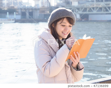 Woman looking at orange notebook on the riverside Woman looking at orange notebook on the riverside 47136899