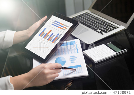 Close-up of hand holding tablet and point pen at chart 47138971