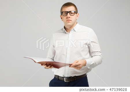 young man in glasses with an open folder in his hands isolated on a light background young man in glasses with an open folder in his hands isolated on a light background 47139028