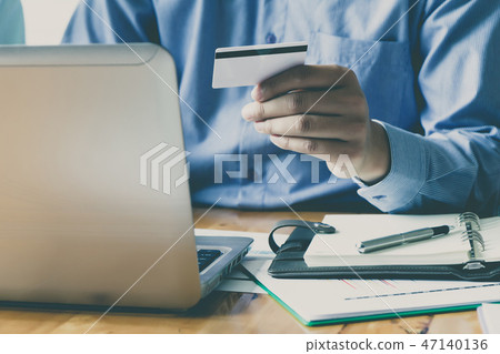 Businessman holding credit card and using laptop. 47140136