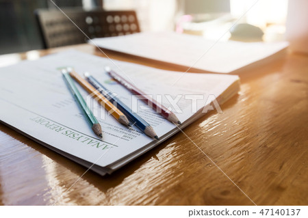 Pencils on report paper on wooden desk. 47140137