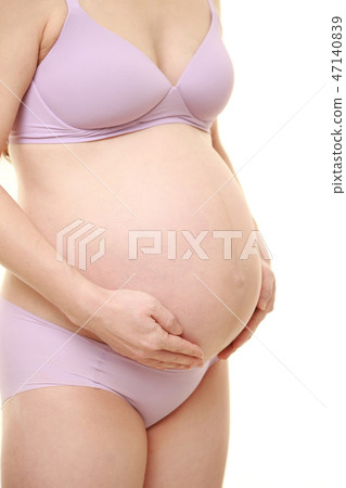 A pregnant woman putting her hand on her stomach 47140839