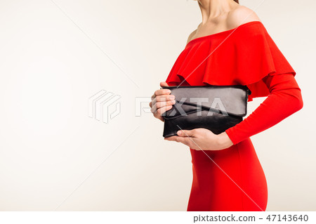 Fashionable woman with a black clutch in her hands and red evening dress 47143640