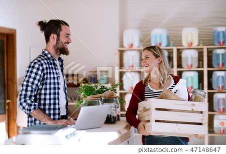Young shop assistant serving an attractive woman in a zero waste shop. Young shop assistant serving an attractive woman in a zero waste shop. 47148647