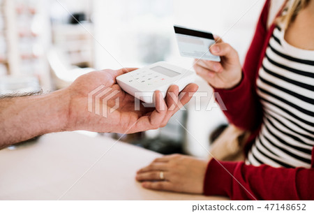 Customer and shop assistant making contactless payment using credit card in a shop. 47148652