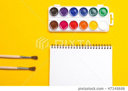 Watercolor paints and brushes with canvas for painting with copyspace on yellow background 47148686
