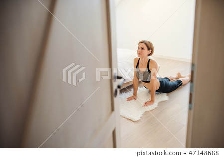 A young woman doing exercise indoors in a bedroom. Copy space. A young woman doing exercise indoors in a bedroom. Copy space. 47148688
