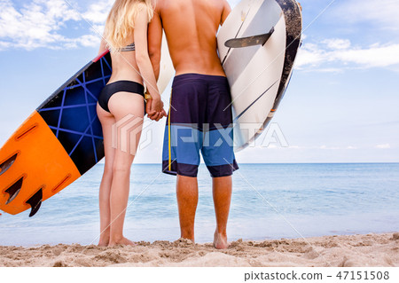 Surfers at the beach- Smiling couple of surfers walking on the beach and having fun in summer 47151508