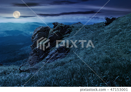 rocky formation on a grassy hillside at night rocky formation on a grassy hillside at night 47153001