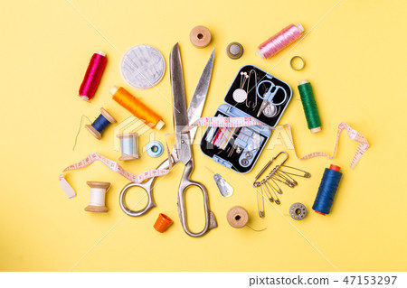 Composition with threads and sewing accessories - scissors, centimeter, pins on yellow background. Composition with threads and sewing accessories - scissors, centimeter, pins on yellow background. 47153297