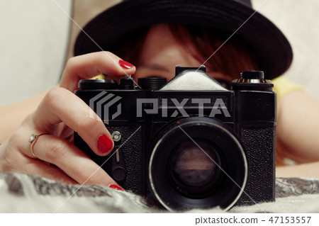 Girl with red hails taking photo using SLR camera in front of her face, vintage color 47153557