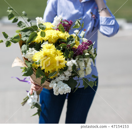 Young woman in blue cotton blouse and jeans holding a bouquet 47154153