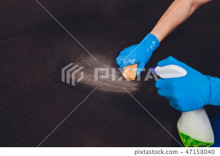 Cropped image. Cleaning concept. Male hand in protective gloves cleaning sofa couch in the room. 47158040