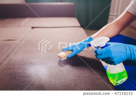 Cropped image. Cleaning concept. Male hand in turquoise, rubber protective gloves cleaning sofa 47158233