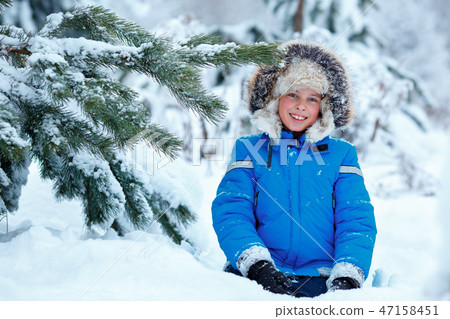 Cute little boy wearing warm clothes playing on winter forest Cute little boy wearing warm clothes playing on winter forest 47158451