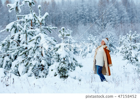 Young pregnant woman wearing warm clothes having fun on winter forest Young pregnant woman wearing warm clothes having fun on winter forest 47158452